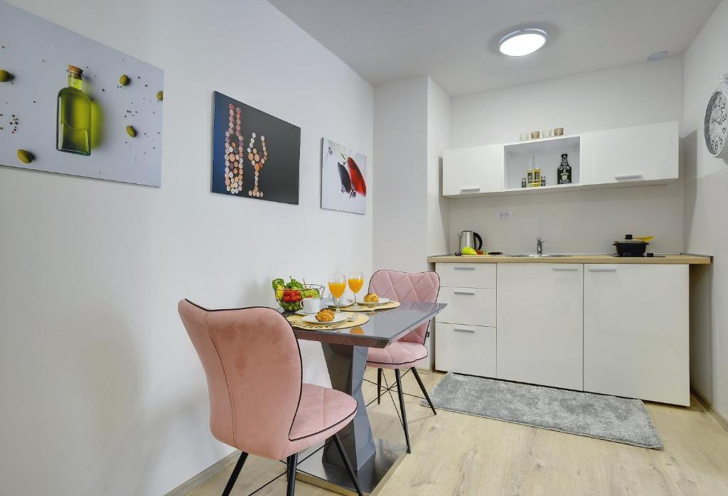 a kitchen with a table and two pink chairs at D&A Amphitheatre Apartments with free parking in Pula