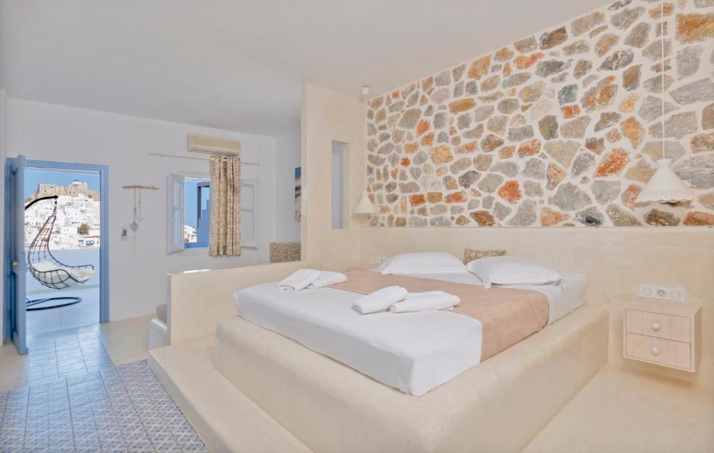 sypialnia z dużym łóżkiem i kamienną ścianą w obiekcie Anatoli Luxury Studios & Suites w mieście Astypalea