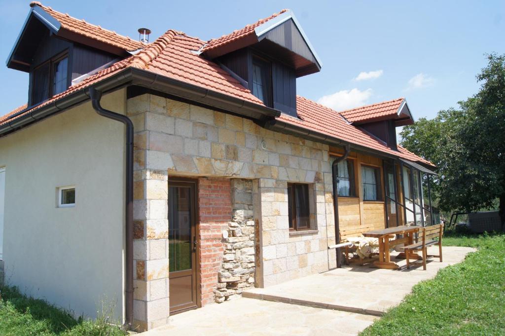 a brick house with a red roof and a bench at Guest House Glogovac in Kamenica