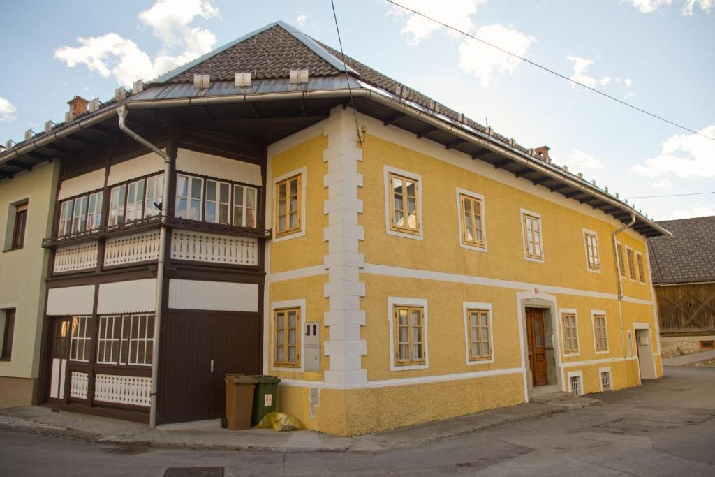 un bâtiment jaune avec un balcon dans une rue dans l'établissement The 1882 Old House Vodnikova, à Bohinj