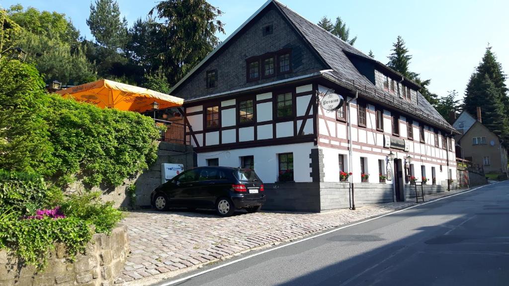 a car parked in front of a white and black building at Meschkes Gasthaus Pension in Hohnstein