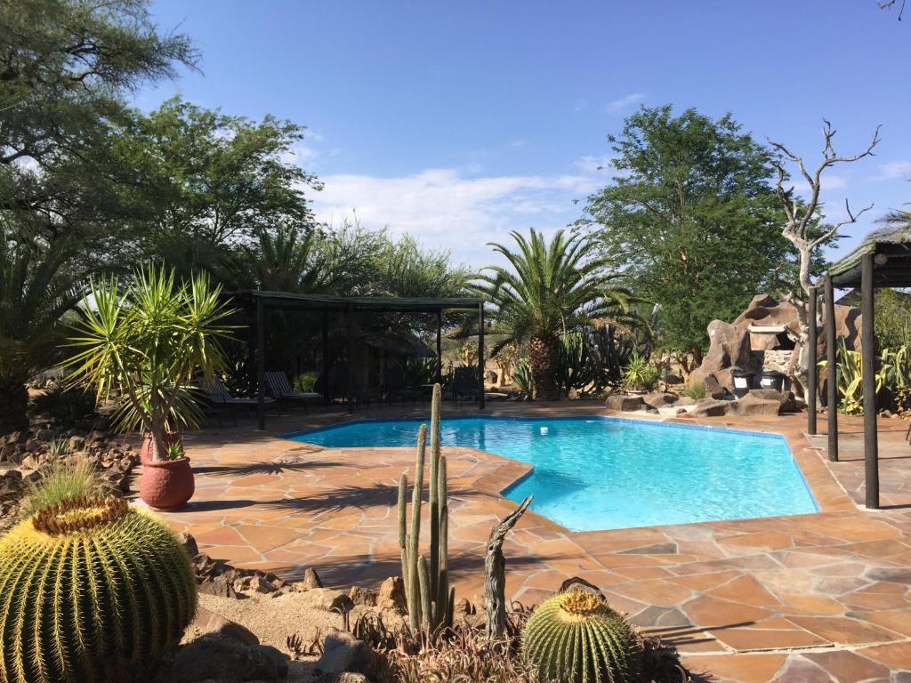 a swimming pool in a garden with cactuses and sidx sidx sidx at Roidina Safari Lodge in Omaruru