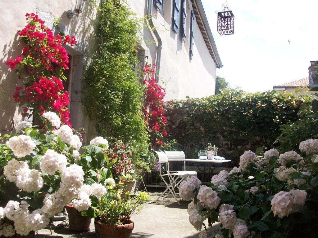 a garden with flowers and a table and a building at Chambres d'Hôtes Aroha in Sorde-lʼAbbaye