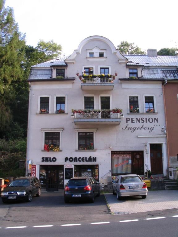 un edificio blanco con coches estacionados frente a él en Apartmany Ingeborg, en Jáchymov