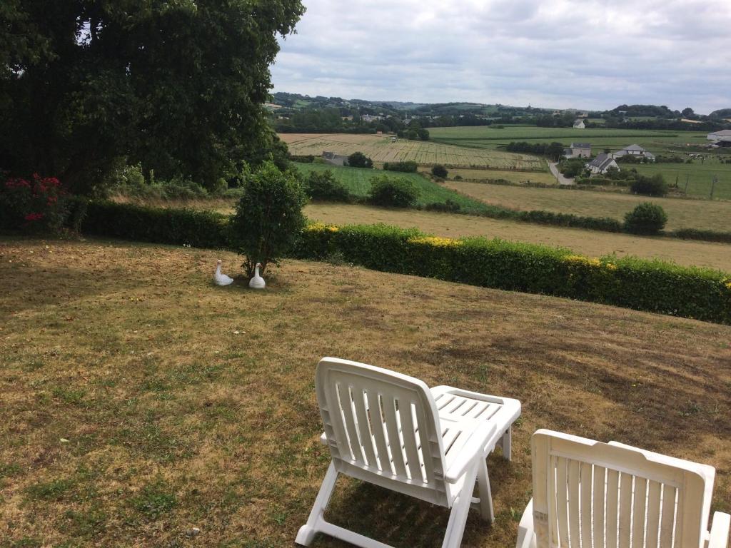 two white chairs sitting on a field with a tree at aux 2 oies in Plouider