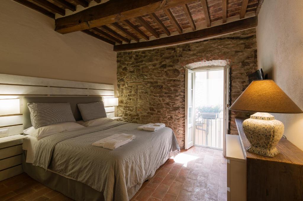 een slaapkamer met een bed en een stenen muur bij Casa Zeni in Cortona
