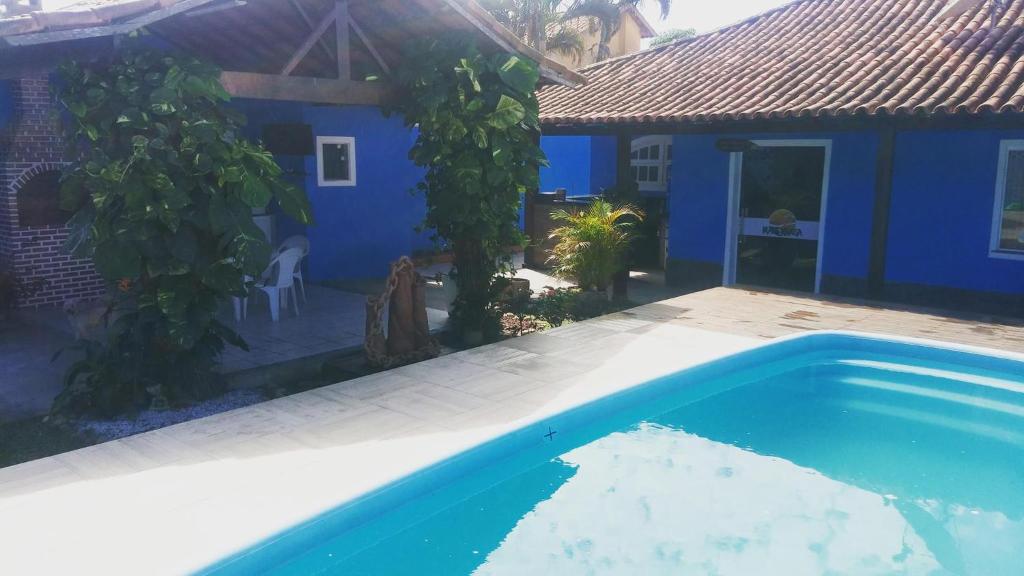 una casa azul con piscina frente a ella en Hostel Maré Mansa en Cabo Frío