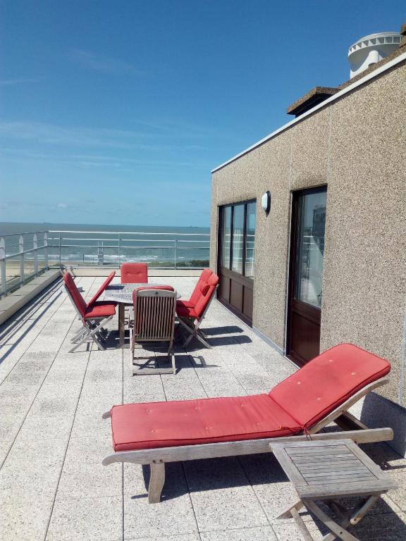 a patio with red chairs and a table on a roof at Penthouse Poseidon in Blankenberge