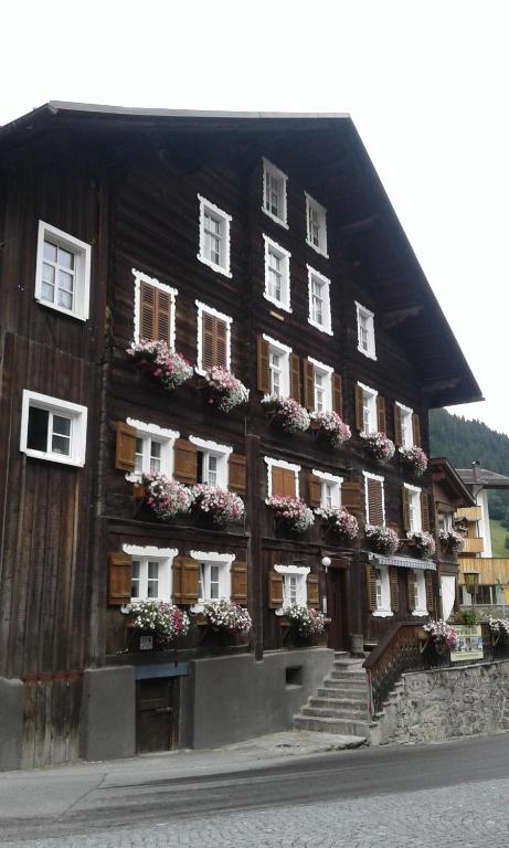 a large wooden building with white windows and flowers at Landhaus-Willi in Gaschurn
