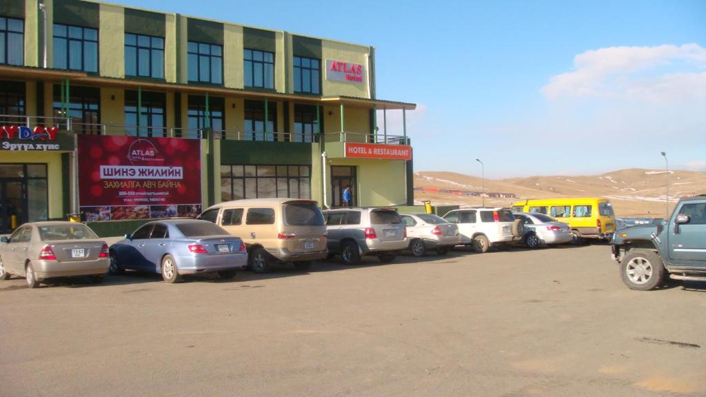 uma fila de carros estacionados em frente a um edifício em Atlas Hotel em Ulan Bator