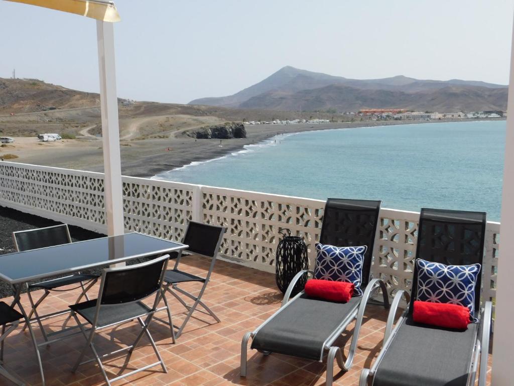 une terrasse avec une table et des chaises et la plage dans l'établissement El Roquito Ocean View, à Tarajalejo
