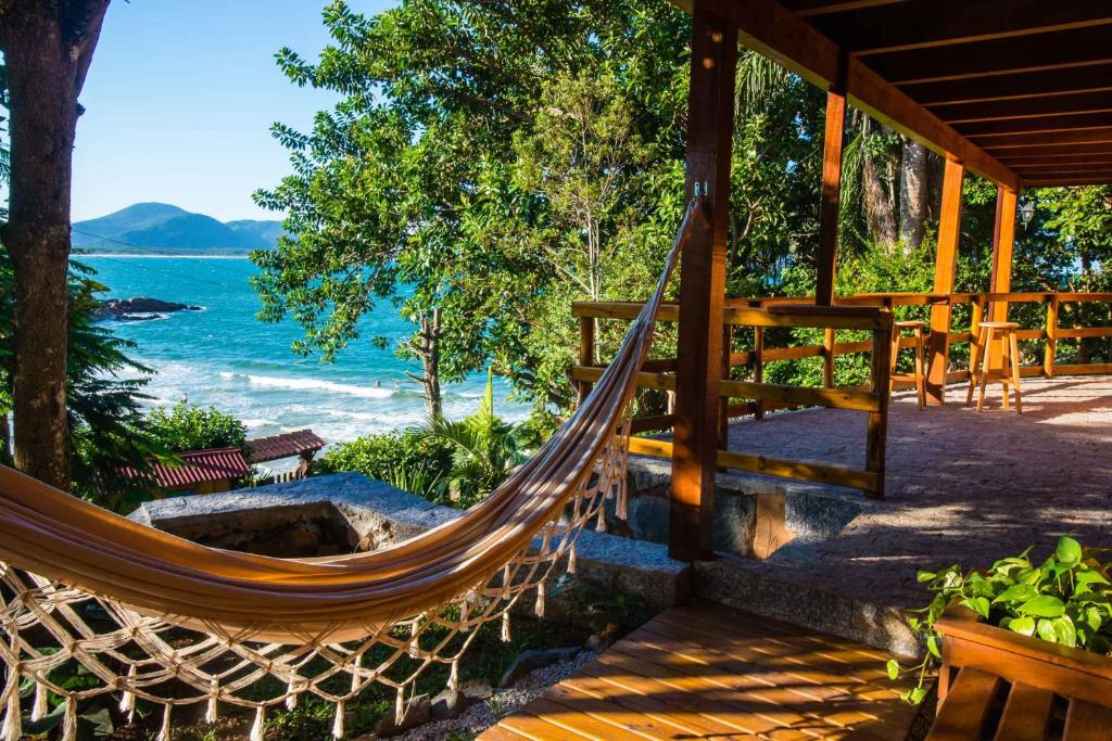 a hammock on a porch with a view of the ocean at Sunset Strip Eco Apartments in Florianópolis