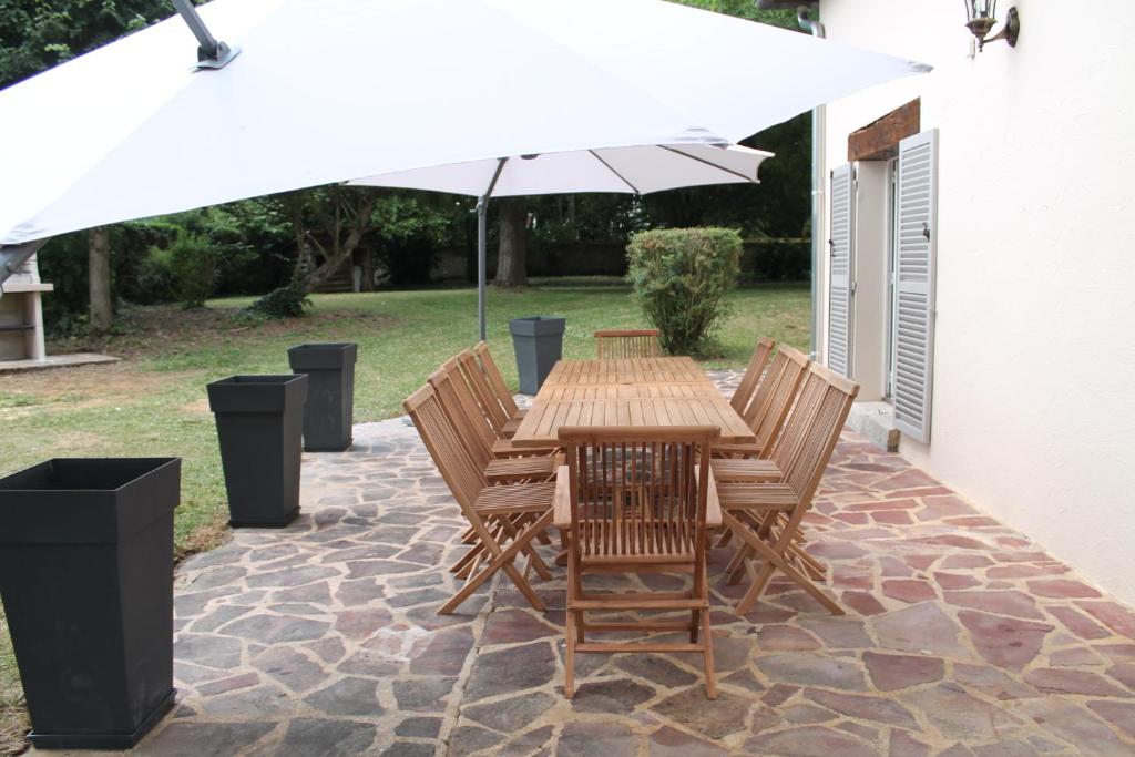 un tavolo in legno e sedie sotto un ombrellone di Villa d'Amoinville a Tilleau
