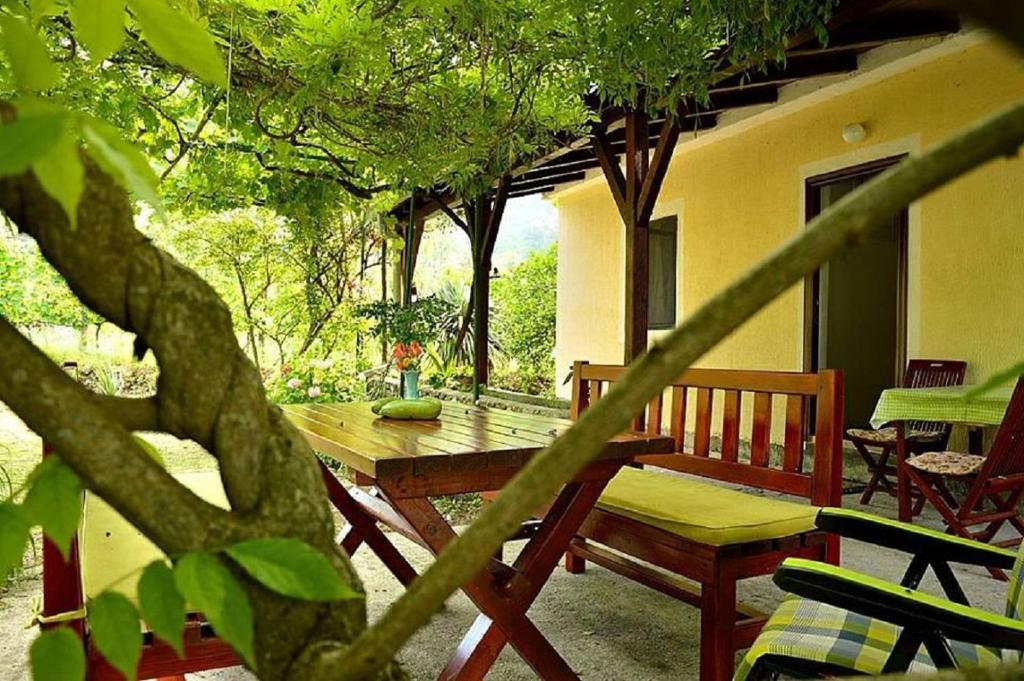 een houten tafel en stoelen op een veranda met bomen bij Ivan's Holiday Home in Virpazar