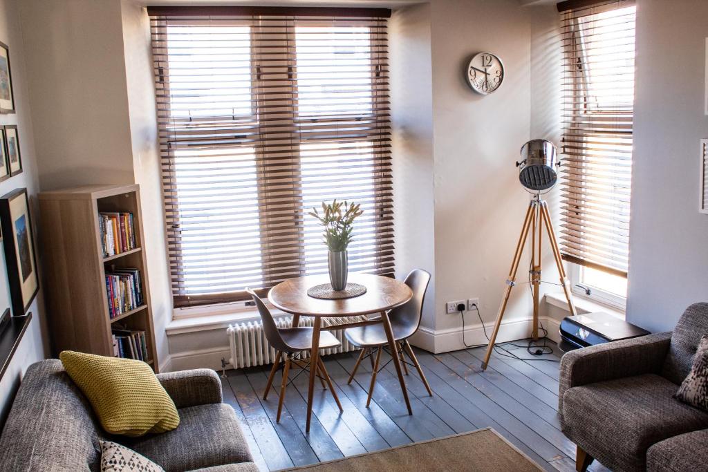 ein Wohnzimmer mit einem Tisch, Stühlen und einem Fenster in der Unterkunft Anchored - Unique Apartment in Glasgow's West End in Glasgow