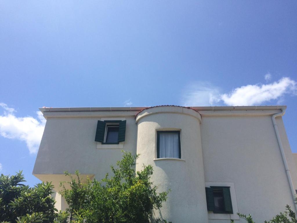 a white building with blue windows on top of it at Villa Lapis Vis in Rukavac