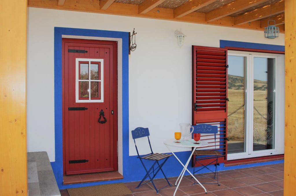 uma casa com uma porta vermelha e uma mesa em Casa dos Corvos em Mértola