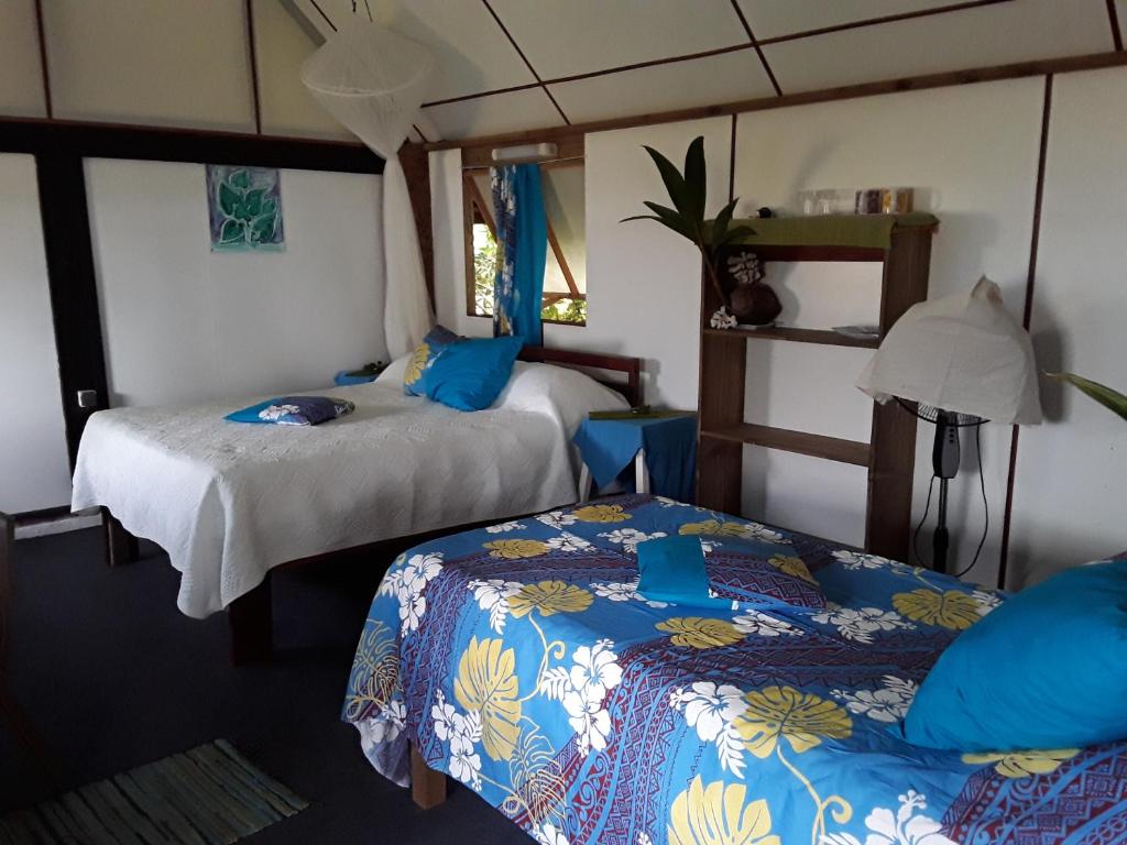 a bedroom with two beds with blue and white sheets at Tifaifai Et Café Huahine in Fare