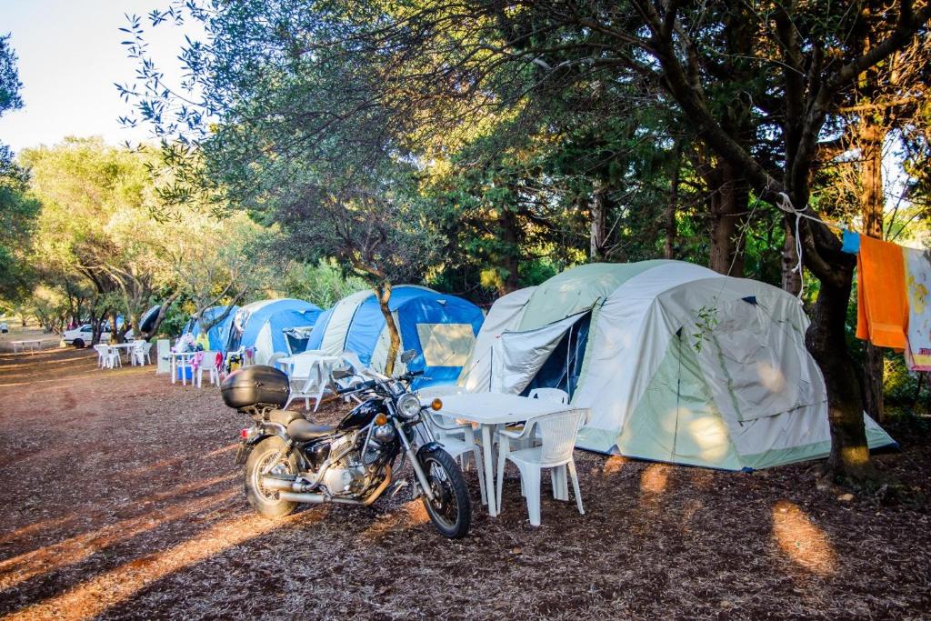 uma moto estacionada em frente a uma fila de tendas em Camping Argostoli em Argostoli