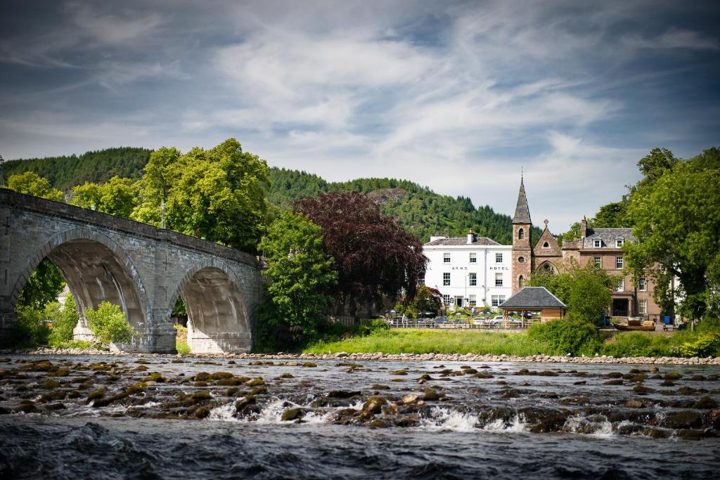 eine Steinbrücke über einen Fluss mit einer Stadt im Hintergrund in der Unterkunft Atholl Arms Hotel Dunkeld in Dunkeld