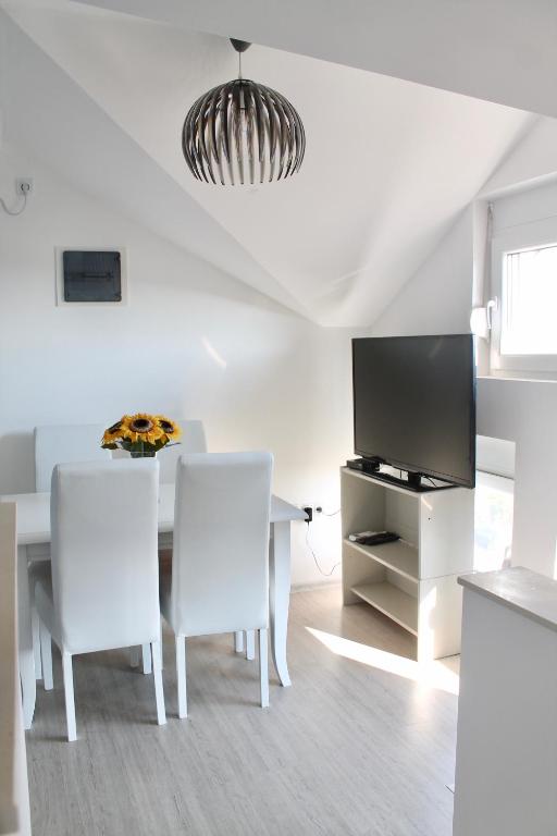 a white dining room with a table and a tv at Apartments Villa Milna 1 in Budva