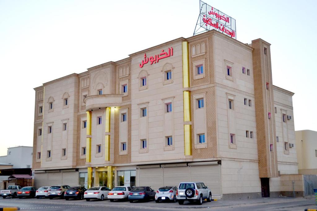 un gran edificio con coches estacionados frente a él en الخربوش للشقق المخدومة en Hafr Al Batin