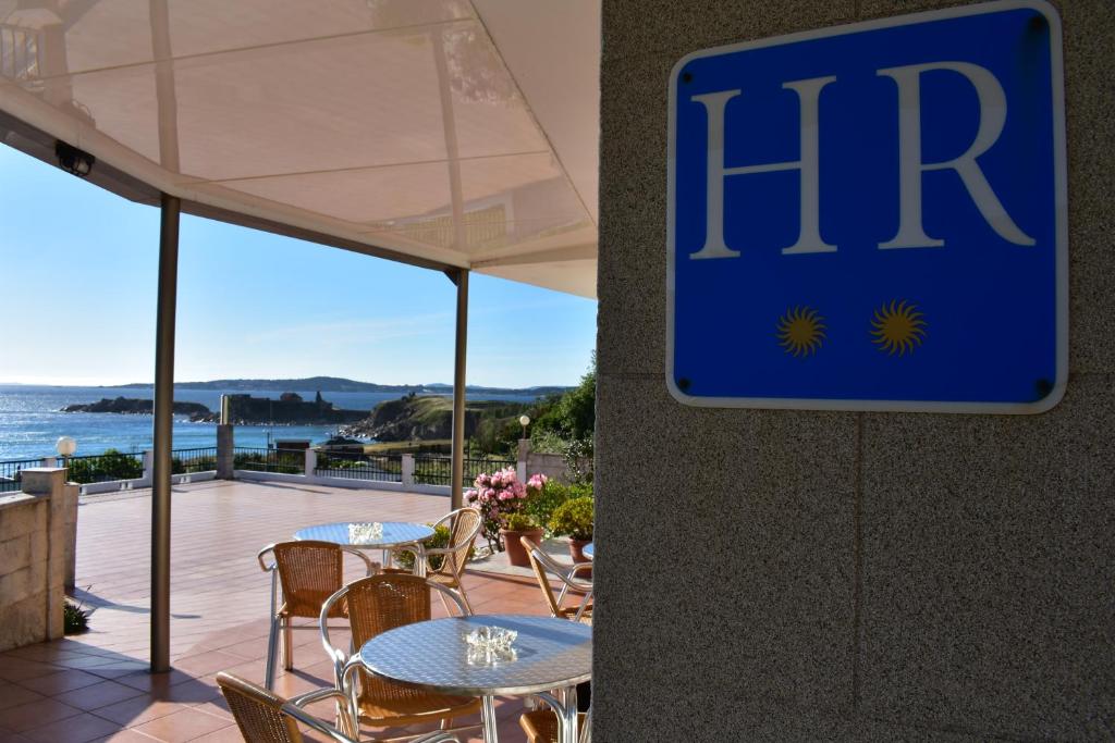 un panneau sur le côté d'un bâtiment avec des tables et des chaises dans l'établissement Hotel Estrella del Mar, à A Lanzada