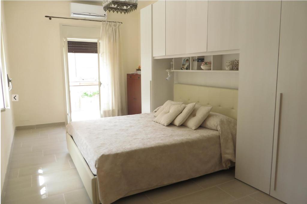 a bedroom with a bed with white walls and a window at La Bouganville in Ioppolo Giancaxio