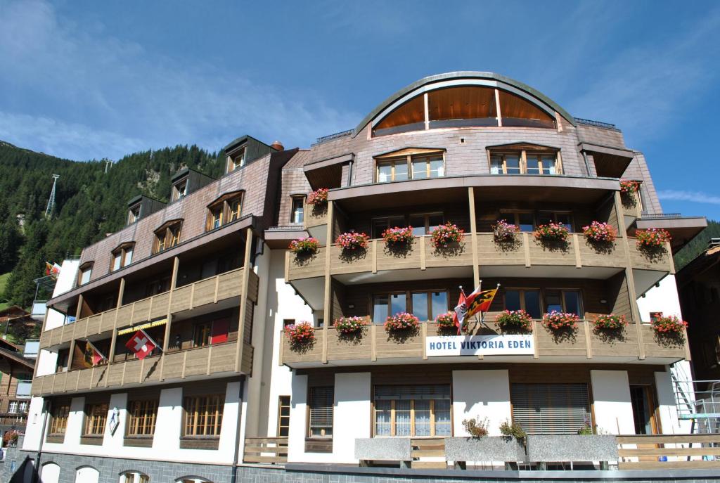 a building with flowers on the balconies of it at Hotel Viktoria Eden in Adelboden