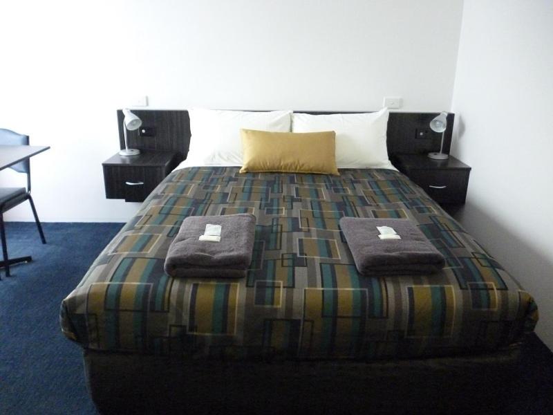 a bedroom with a bed with two towels on it at Otway Gate Motel in Colac