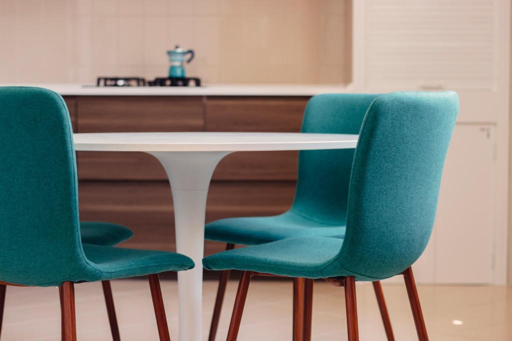 3 grüne Stühle um einen weißen Tisch in der Küche in der Unterkunft Alchimia Apartment in Conversano