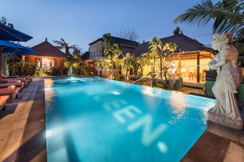 ein Schwimmbad mit einer Statue neben einem Haus in der Unterkunft Queen Villa in Nusa Lembongan