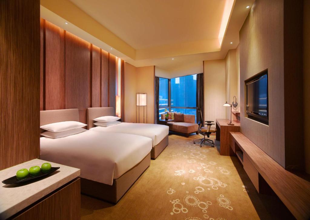Cette chambre comprend deux lits et une télévision. dans l'établissement Hyatt Regency Guiyang, à Guiyang