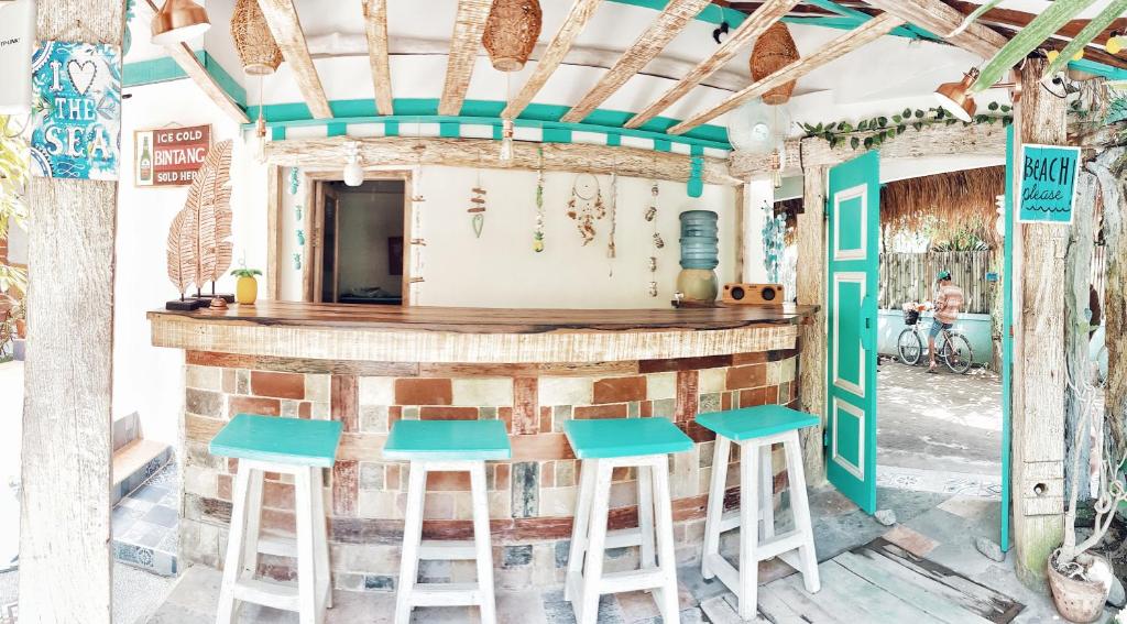a bar with blue stools in front of a building at Havana Hideaway in Gili Trawangan