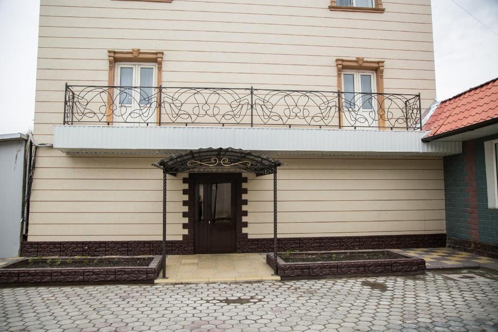 a white building with a balcony and a door at Mirage Hotel in Qyzylorda