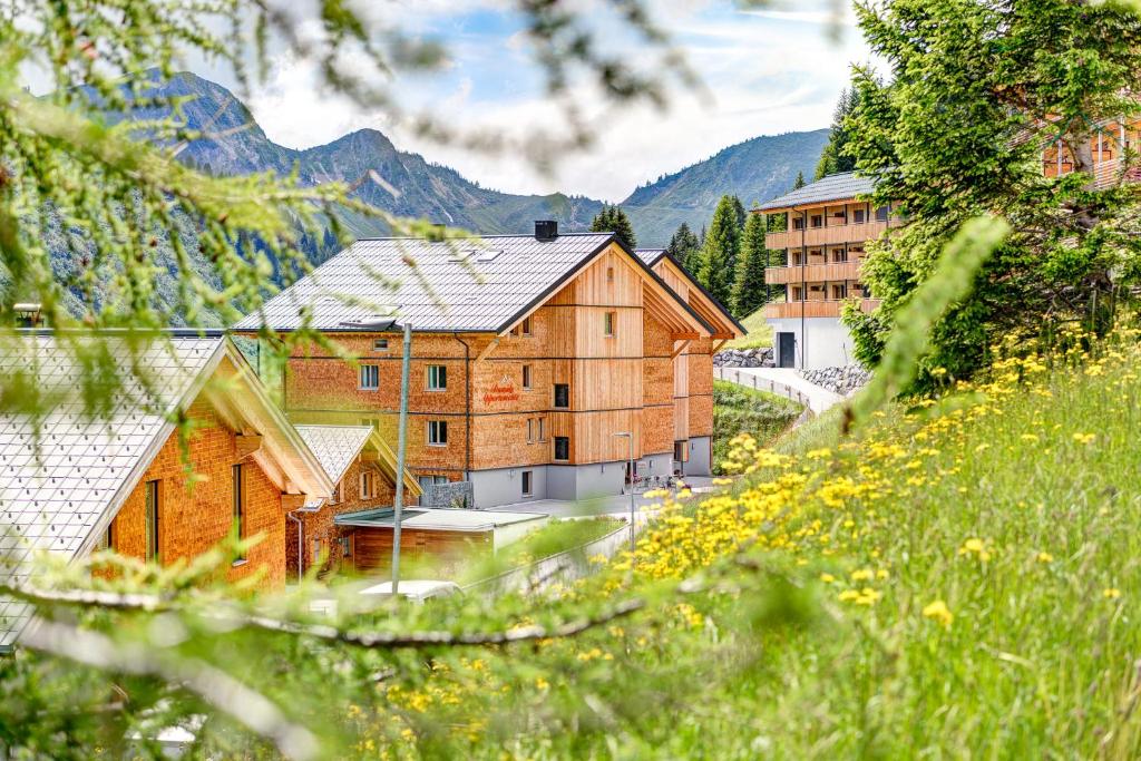 a large wooden building in a field of flowers at Damüls Appartements in Damuls