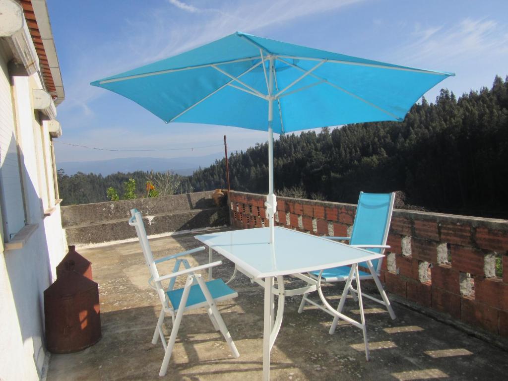 uma mesa e duas cadeiras e um guarda-chuva azul em Casa Eira do Povo 1 em Vale de Colmeias