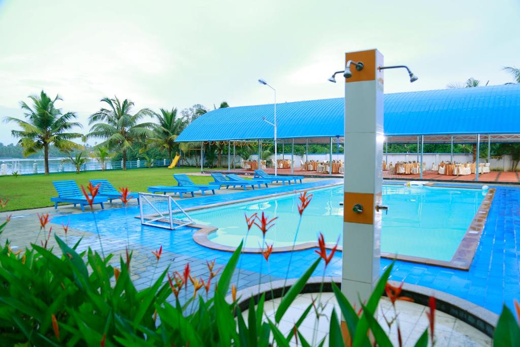 a large swimming pool with blue tables and chairs at Renai Blue Waters Cherai in Cherai Beach