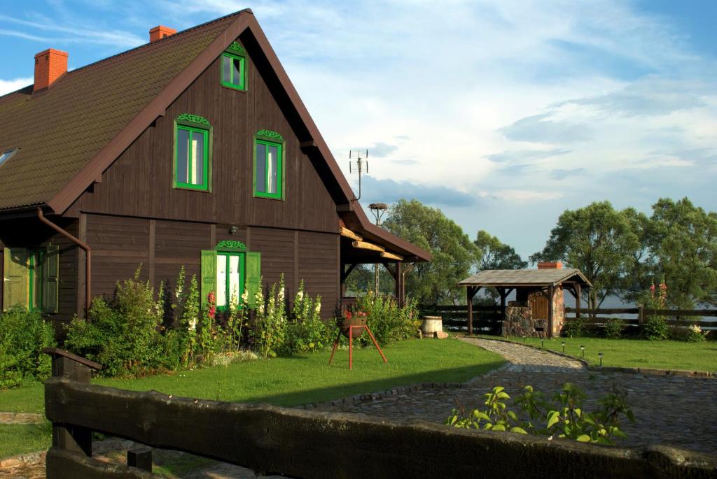 ein Haus mit grünen Fenstern und einem Hof in der Unterkunft Pluszkiejmy 44 in Pluszkiejmy