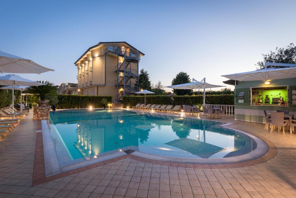 ein großer Pool mit Stühlen und ein Gebäude in der Unterkunft Hotel Villa Tiziana in Marina di Massa