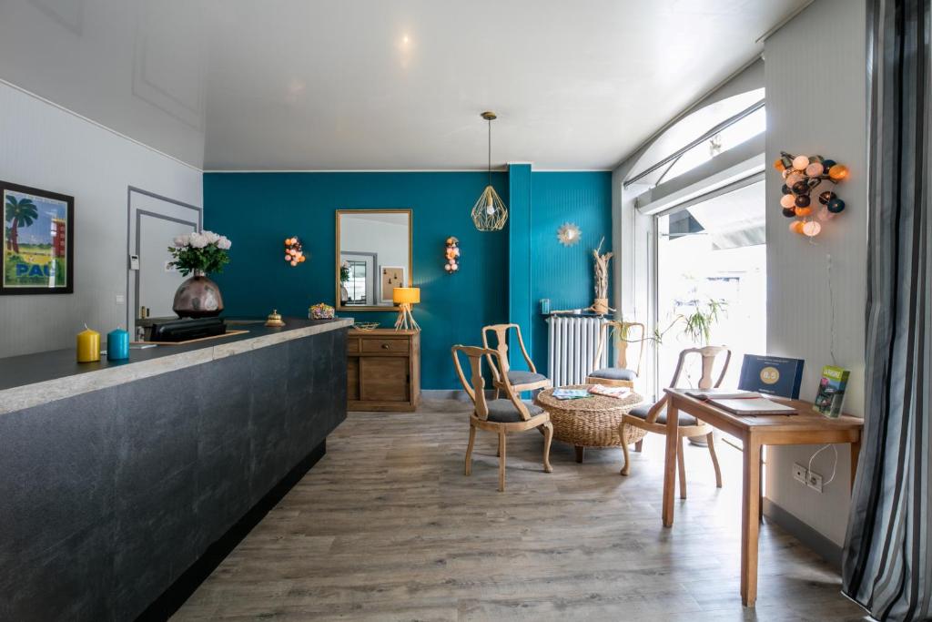 ein Wohnzimmer mit blauen Wänden sowie einem Tisch und Stühlen in der Unterkunft Hôtel Central in Pau