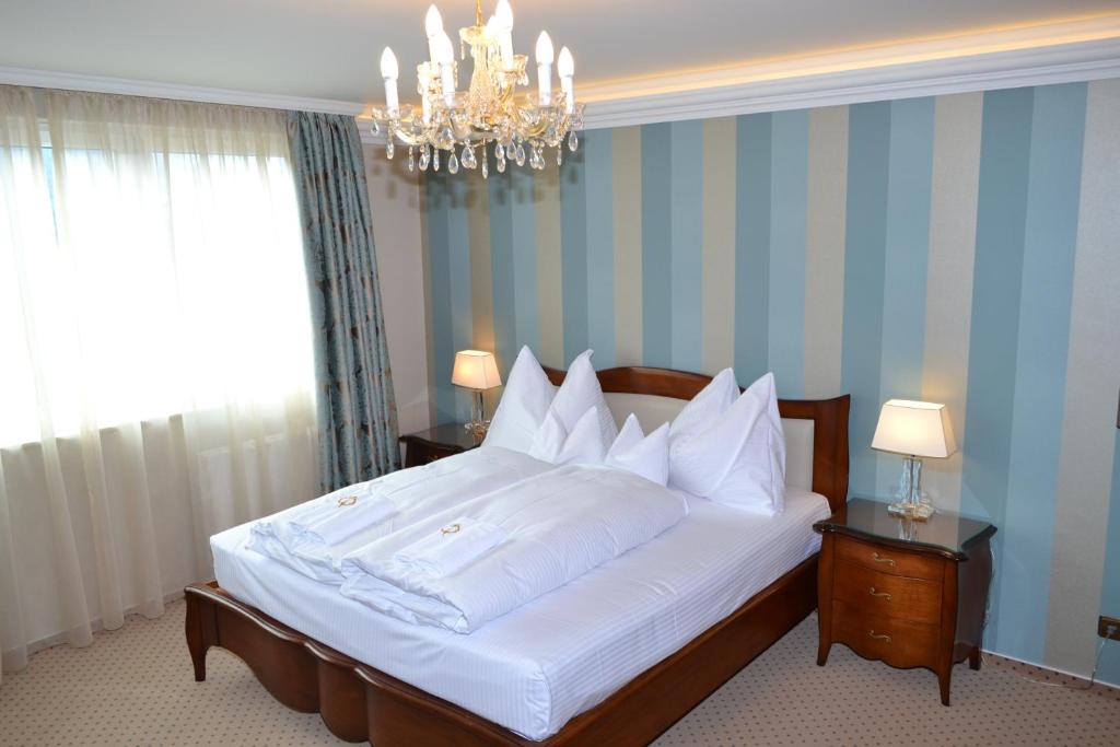 - une chambre avec un grand lit blanc et un lustre dans l&#39;établissement Hotel zum Heiligen Geist, à Mariazell