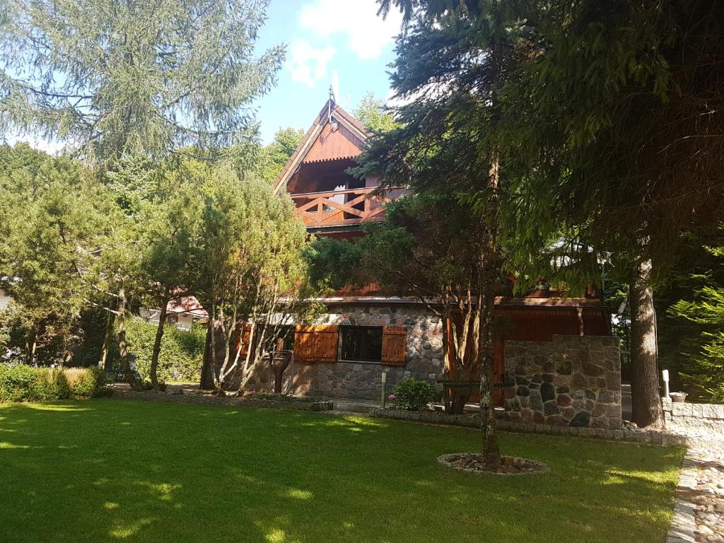 uma casa com um relvado verde em frente em Kashubia Cottage em Przewóz