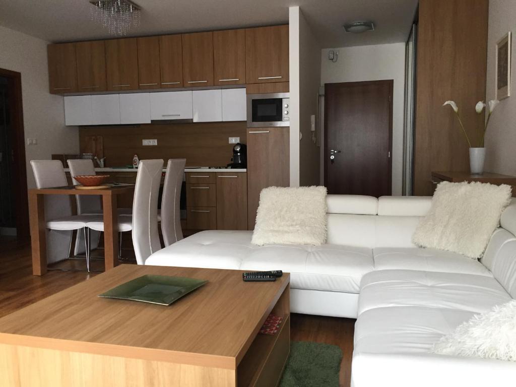 a living room with a white couch and a kitchen at Apartman Tale in Tale