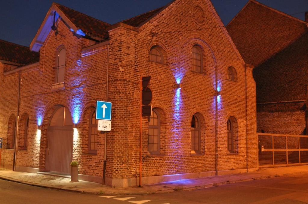 un bâtiment en briques avec des lumières sur son côté dans l'établissement Blue House On The Water, à Courtrai