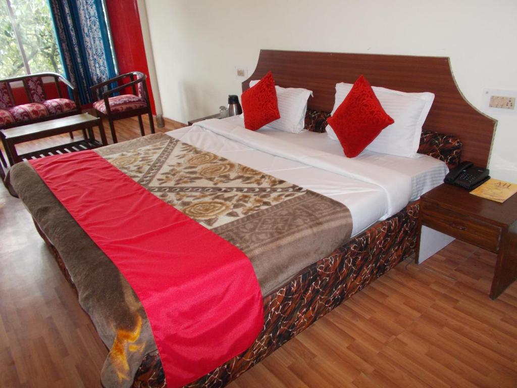 a bedroom with a large bed with red pillows at Anamika Hotel in Nainital