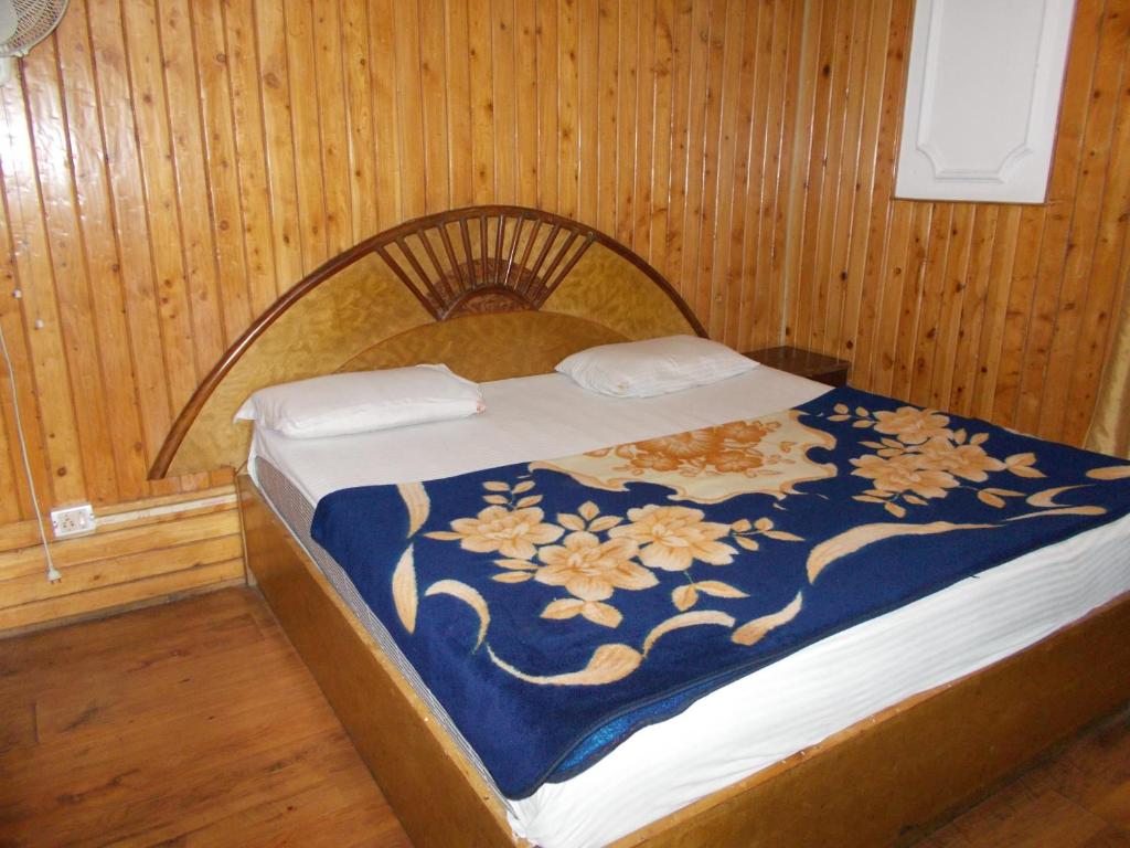 a bed in a room with a blue and white blanket at Mall road Stay with In-house restaurant in Nainital