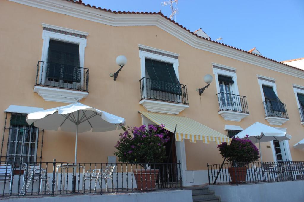 un edificio con sillas y sombrillas delante de él en Hotel Varinia Serena - Balneario de Alange en Alange