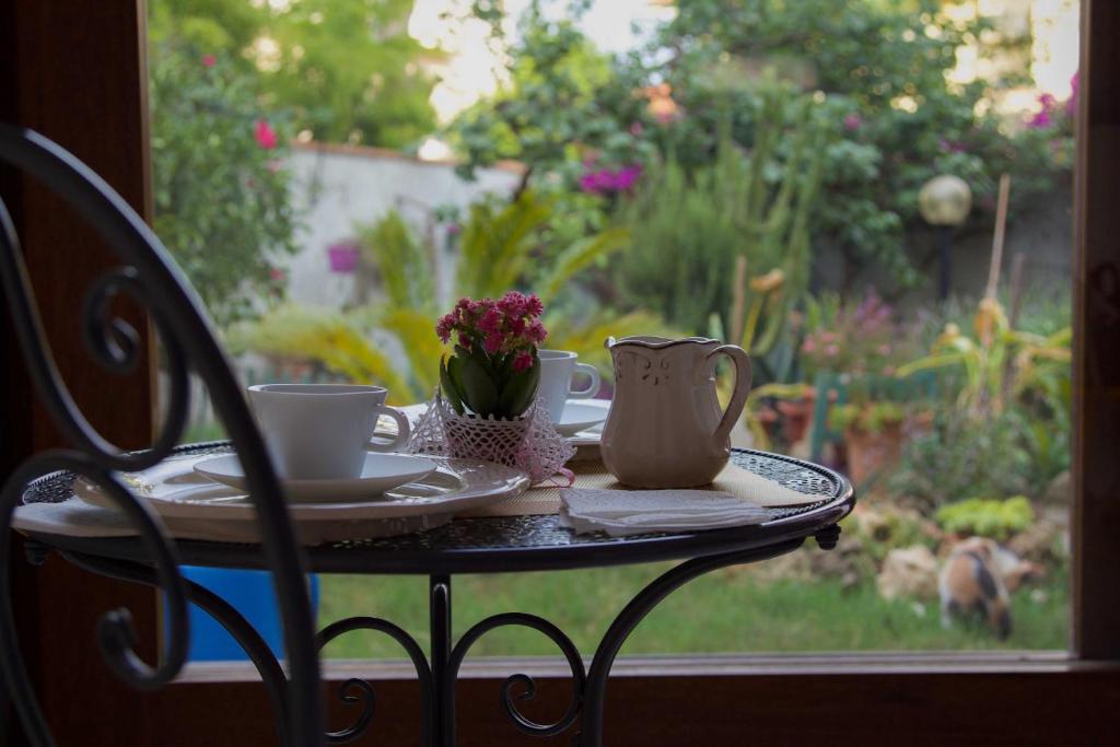 einen Tisch mit zwei Tassen und eine Vase mit Blumen darauf in der Unterkunft Angolo Verde in Oristano