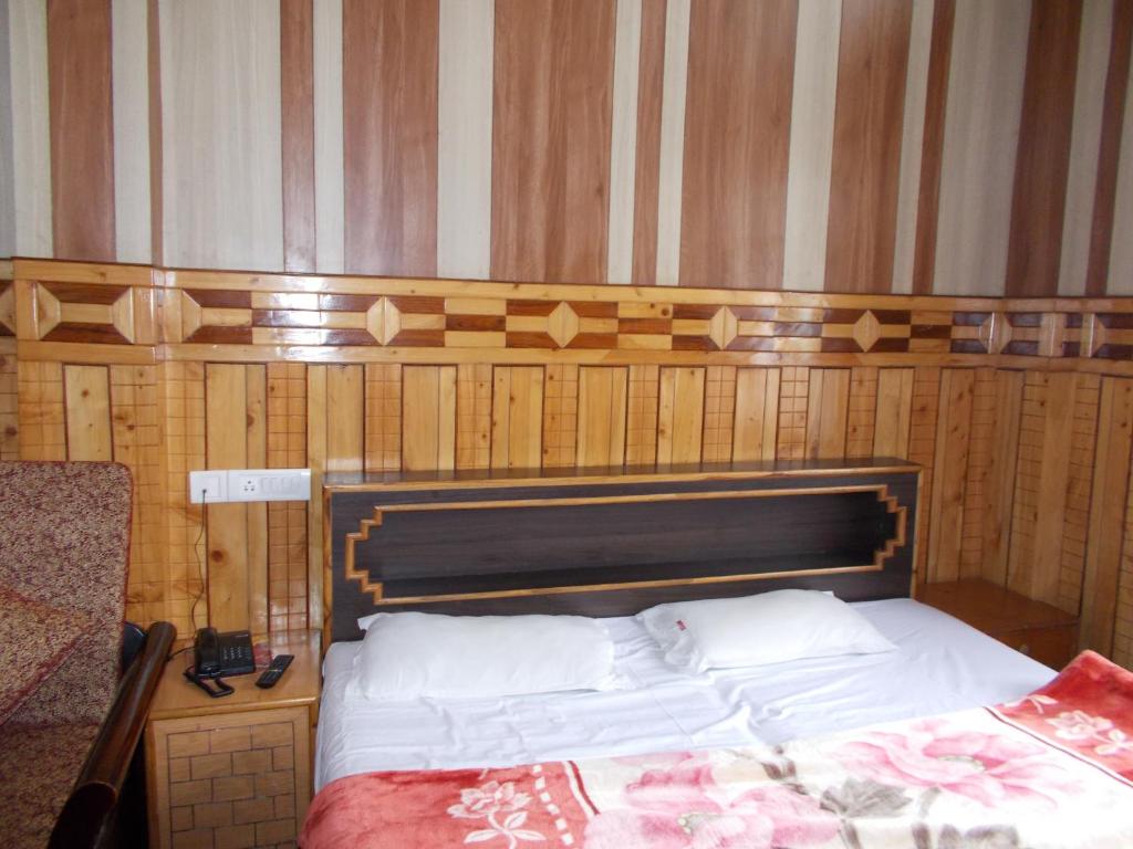 a bed in a room with a wooden wall at Perfect Family Stay next to Nainital Lake in Nainital